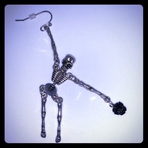 Skeleton dangle earring holding a black rose